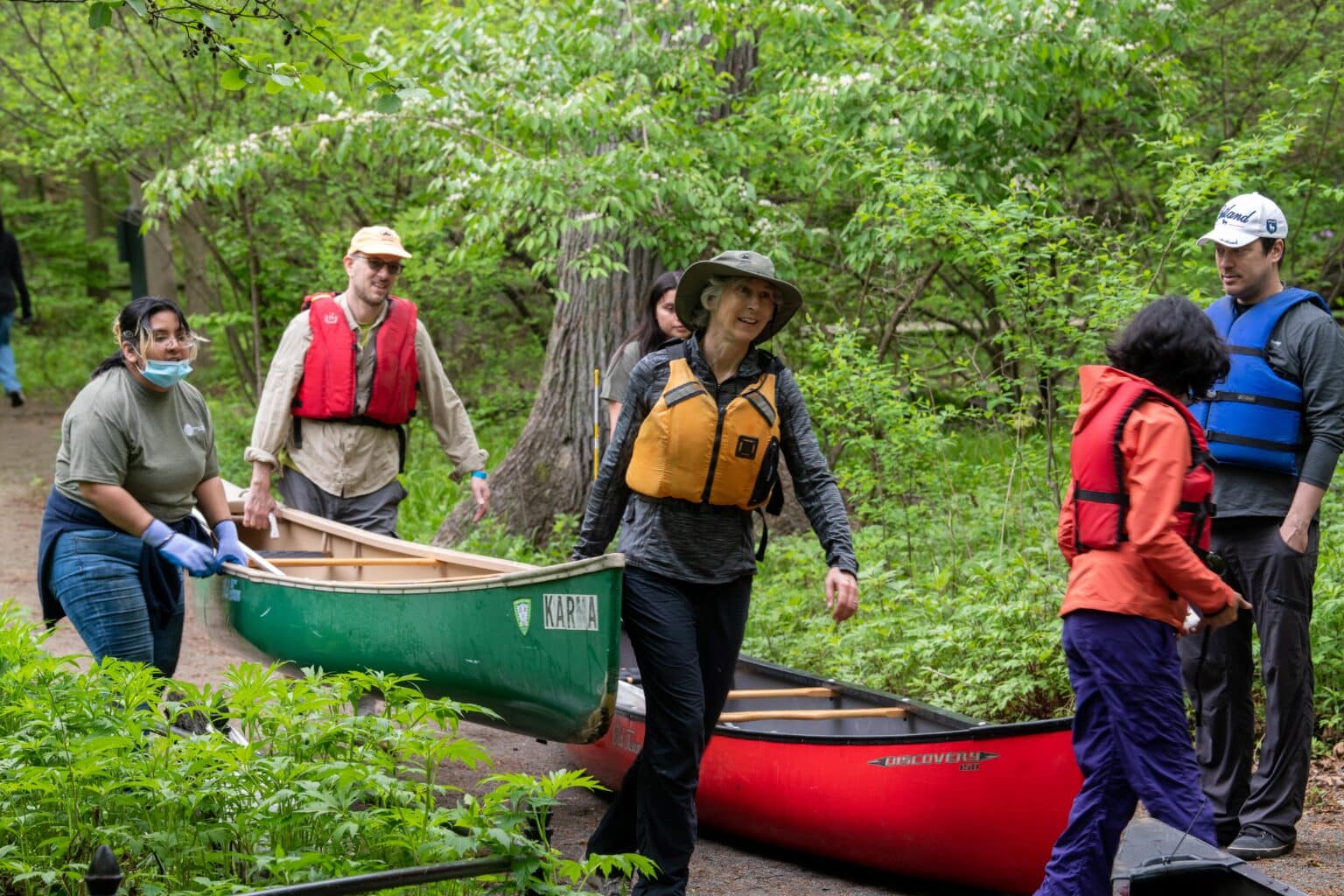 Paddlers with life jackets carrying canoes